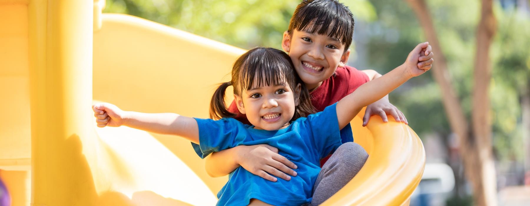 a couple of kids on a yellow slide